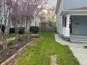 Charming side yard featuring a lush lawn, brick-edged garden, and flowering trees between two light blue houses at 2250 N Capitol Ave, Indianapolis, IN 46208