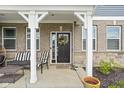 Inviting front porch features a seating area with cozy furniture and charming decorative touches and front door with wreath at 2536 Maricopa Blvd, Whitestown, IN 46075