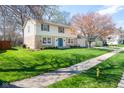 Beautiful two-story house with stone details, a blue front door, green lawn and mature trees at 3738 Barrington Dr, Carmel, IN 46033