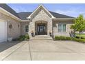 Elegant brick home entrance featuring a stone archway, complemented by a well-manicured lawn and greenery at 5348 Ashby Ct, Greenwood, IN 46143