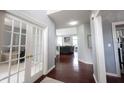 Hallway with wood floors, glass-paned doors, and a view into the living room and office space at 8748 N Autumnview Dr, McCordsville, IN 46055