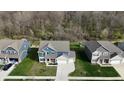 Aerial view of a home showing the roof, lawn, and neighborhood homes with a wooded area at 9207 Foudray N Cir, Avon, IN 46123