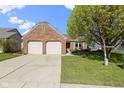 Charming brick home featuring a two-car garage, manicured lawn and mature shade tree at 9526 Colony Pointe E Dr, Indianapolis, IN 46250