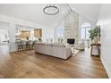 Bright living room with stone fireplace, hardwood floors, and a view into the kitchen at 12536 Lowery Way, Fishers, IN 46037
