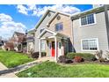 Attractive condo building with lush green lawn, mature bushes, and a welcoming red entry door at 12588 Tennyson Ln # 205, Carmel, IN 46032