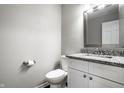 Well-lit bathroom features granite counters, white vanity, modern toilet and decorative framed mirror at 156 Aspen Way, Carmel, IN 46032