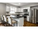 Modern kitchen with white cabinets, stainless steel appliances, black countertops and bar stool seating at 156 Aspen Way, Carmel, IN 46032