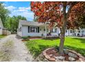 Charming single-story home featuring a well-kept lawn, American flag, and lovely landscaping around the trees at 1629 N K St, Elwood, IN 46036