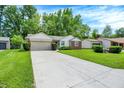 Well-kept single-story home boasts a lush green lawn and a long driveway to the attached garage at 1697 Stacy Lynn Dr, Indianapolis, IN 46231