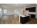 Open-concept kitchen featuring dark cabinets, an island with a sink, and hardwood floors throughout at 2268 Marjorie Way, Shelbyville, IN 46176