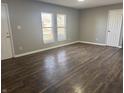 An empty living room ready for its new occupants offers hardwood flooring and two windows for light at 3642 Horth Ct, Indianapolis, IN 46235