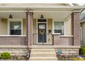Inviting covered front porch with brick pillars, black railing and a wreath on the front door at 420 Orange St, Indianapolis, IN 46225