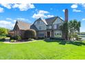 Beautiful traditional-style home with lush front lawn, mature trees, and lake views on a sunny day at 4843 Snowberry Bay Ct, Carmel, IN 46033