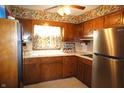 Cozy kitchen featuring ample wooden cabinetry, floral wallpaper, a stainless steel refrigerator, and bright natural light at 5363 Channing Rd, Indianapolis, IN 46226