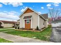 Side view of the tan house featuring a detached garage and small cedar details at 604 Wood St, Greenfield, IN 46140