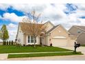 Traditional home features a well-manicured lawn, mature tree, and convenient three-car garage at 6717 Marble Arch Way, Indianapolis, IN 46259