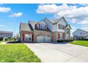 Two-story home featuring brick, attached garage, a long driveway, red shutters and a well manicured lawn at 7637 Sand Run Ct, Indianapolis, IN 46259