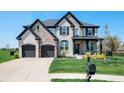 Beautiful two-story home with a well-manicured lawn and a charming front porch with black accents and stone details at 8452 Ironhill Ct, Indianapolis, IN 46259