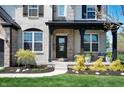 Charming covered front porch with decorative plants, black door, and a welcoming entryway, surrounded by greenery at 8452 Ironhill Ct, Indianapolis, IN 46259