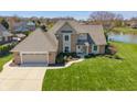 Aerial view of a brick home featuring a manicured lawn extending to a serene lake at 1016 Silver Lake Ct, Greenwood, IN 46142