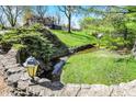 Scenic creek flowing through the lush backyard, with a charming stone bridge at 11625 Rolling Springs Dr, Carmel, IN 46033