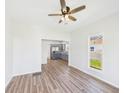 Bright living room featuring light walls, wood floors, and a ceiling fan; kitchen visible in background at 1217 W 6Th St, Anderson, IN 46016