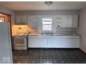 Functional kitchen with white cabinets, laminate countertops, standard appliances, and a window over the sink area at 1618 E 24Th St, Muncie, IN 47302