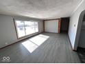 Bright living room featuring wood-look tile, a large picture window, and neutral walls, creating a welcoming space at 1618 E 24Th St, Muncie, IN 47302