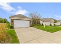Beautiful single-story home with a two-car garage and a lush green lawn and landscaping at 16243 Oliver St, Fishers, IN 46037