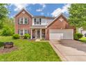 Traditional brick two-story home featuring a two-car garage, a cozy front porch, and manicured green lawn at 2303 Cole Wood Ct, Indianapolis, IN 46239