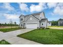 Charming gray home featuring a long driveway, well-manicured lawn, and lush landscaping at 2764 Glade Ave, Plainfield, IN 46168