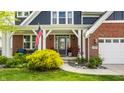 Inviting covered porch with an American flag, colorful flower pots, and a charming seating area at 3640 Snowdon Dr, Westfield, IN 46074