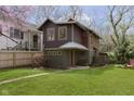 View of the home with wood fence, mature trees and lush green grass at 5110 Riverview Dr, Indianapolis, IN 46208