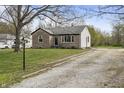 Stone facade home with a long gravel driveway, mature trees, and a well-maintained lawn at 6107 Rural Dr, Indianapolis, IN 46227
