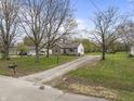 Exterior view of a stone house with a gravel driveway and mature trees at 6107 Rural Dr, Indianapolis, IN 46227