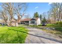 Charming single-story home features a long driveway, stone accents, and a lush green lawn at 7008 E Jackson St, Muncie, IN 47303