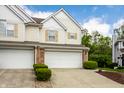 Townhome with a white garage door, yellow shutters and trimmed green bushes at 9338 Eden Woods Ct, Indianapolis, IN 46260
