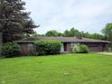 Brick home with mature landscaping including trees and bushes, and a well-maintained lawn at 935 Fry Rd, Greenwood, IN 46142