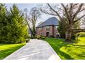 Classic brick home with a circular driveway, mature trees, and well-manicured landscaping at 10605 Winterwood, Carmel, IN 46032