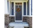 Close up of front door with wreath, classic lantern and stylish brick accents on a charming exterior at 11880 Whisper Ridge Dr, Noblesville, IN 46060