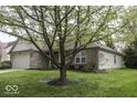 Exterior view of a single-story home featuring mature tree and a well-maintained lawn at 12249 E Harvest Glen Dr, Cumberland, IN 46229