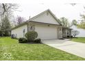 Exterior view of a single-story home featuring an attached two-car garage and well-maintained landscaping at 12249 E Harvest Glen Dr, Cumberland, IN 46229