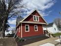 Side view of a red two-story home with a gabled roof, black foundation, and landscaped yard at 128 W Walnut St, Lebanon, IN 46052
