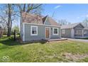 Charming bungalow featuring a light green exterior, a brown roof, and a small, quaint front yard at 1409 S Kiel Ave, Indianapolis, IN 46241