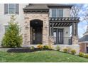 Close-up of a home's entrance with stone accents, a dark door, and a cozy, inviting porch at 14872 Autumn View Way, Fishers, IN 46037