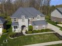 Aerial view of a brick and stone home with an attached garage, long driveway, and green lawn at 2798 W High Grove Cir, Zionsville, IN 46077