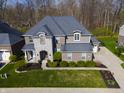 Aerial view of a brick and stone home with an attached garage, long driveway, and green lawn at 2798 W High Grove Cir, Zionsville, IN 46077