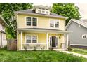 Inviting yellow two-story home with a cozy front porch, showcasing curb appeal and charm at 3133 Ruckle St, Indianapolis, IN 46205