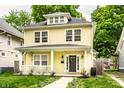 Classic two-story yellow home featuring a charming front porch and mature landscaping at 3133 Ruckle St, Indianapolis, IN 46205
