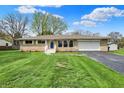 Attractive one-story home with stone facade, attached garage, and lush green lawn at 6826 Hague Rd, Indianapolis, IN 46256